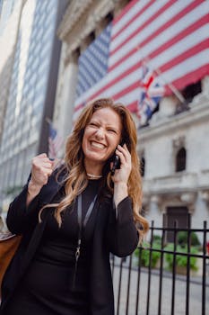 Excited businesswoman celebrates success outside a government building with US and UK flags.