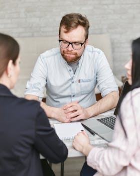 Professional business meeting with a bearded man and two colleagues in an office setting.